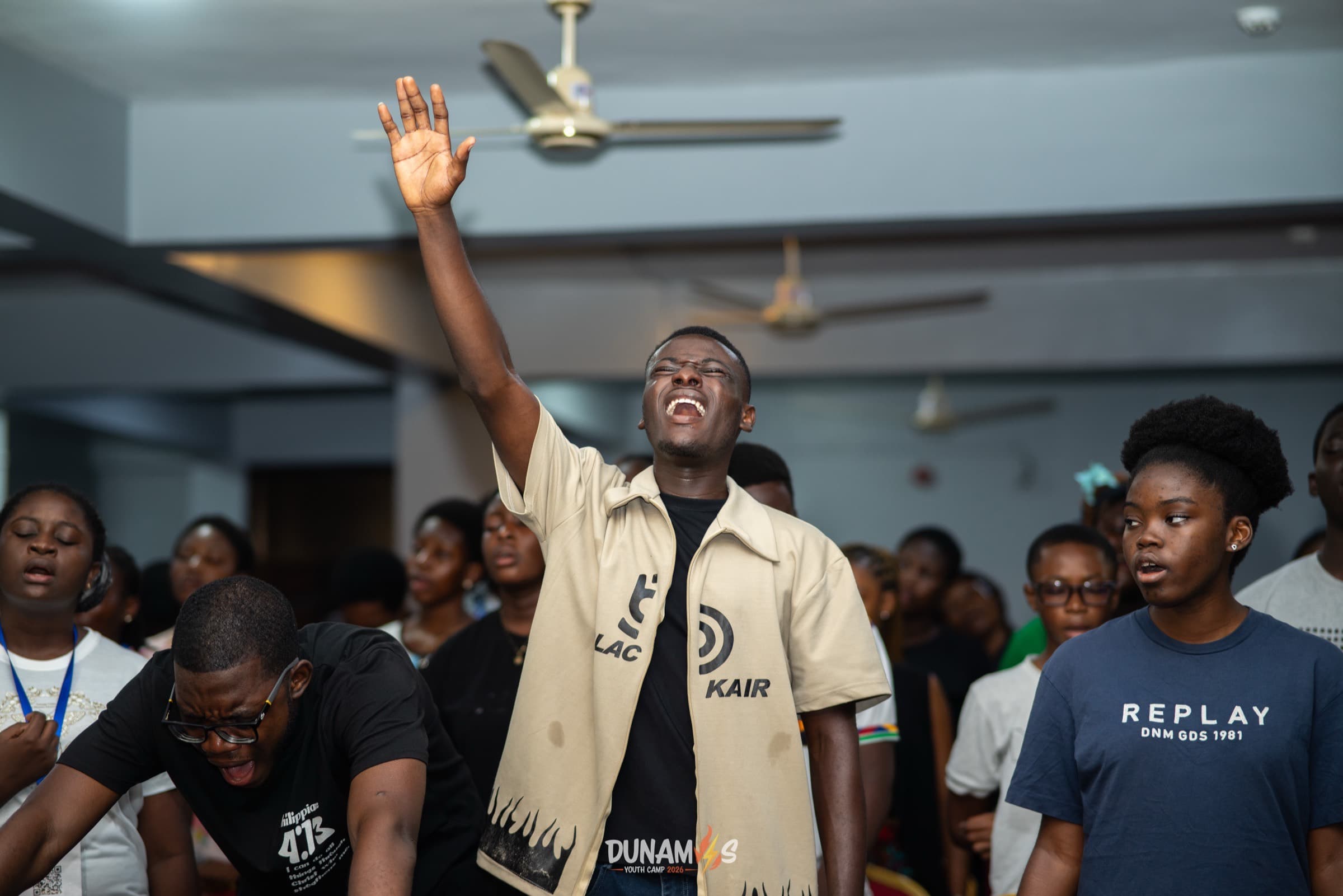 Campers standing with hands raised during a worship session