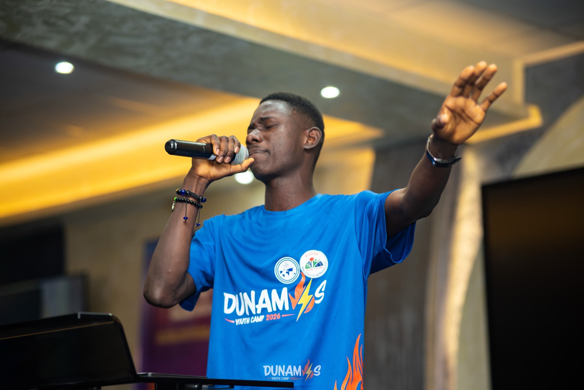 A camper leading a song with his arm outstretched