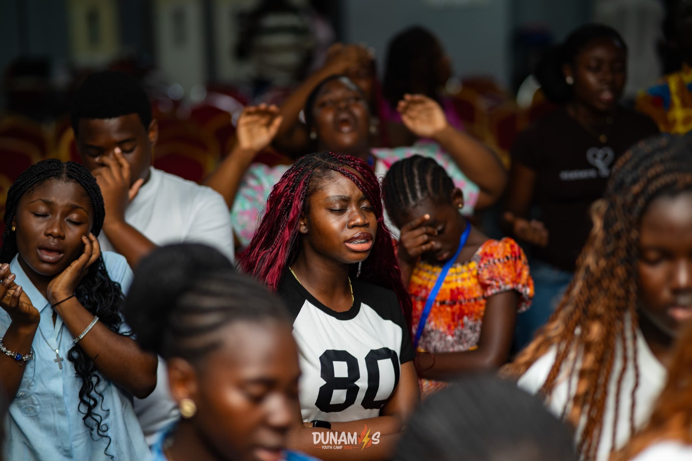 Campers praying together with hands raised